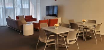 A modern living room with a grey sofa, red chairs, and a white coffee table.