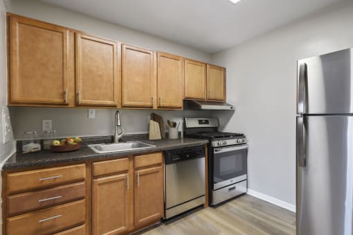 an empty kitchen with wooden cabinets and stainless steel appliances at Earle Manor Apartments, Wheaton, MD