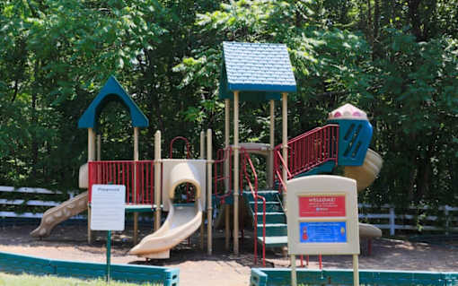 A playground with a slide, a treehouse, and a sign that says at Ellicott Grove, Ellicott City, MD 21043