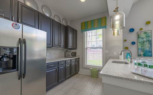 A kitchen with a stainless steel refrigerator and black cabinets at Ellicott Grove, Ellicott City, MD 21043