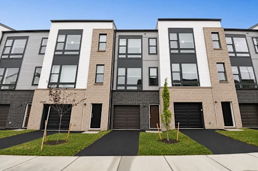 A modern apartment building with a black and white facade and a small tree in front.