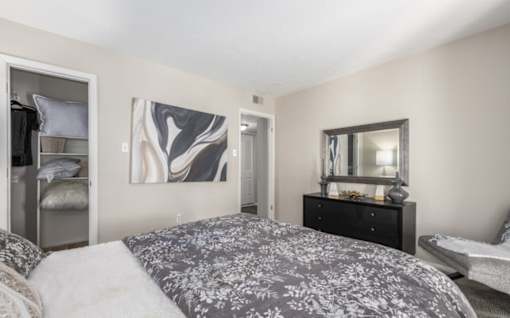 A bedroom with a large bed and a dresser with a mirror at Madison at Eden Brook, 21046