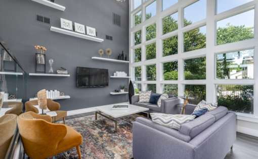 A living room with a grey couch, a yellow chair, and a coffee table at Madison at Eden Brook, 21046