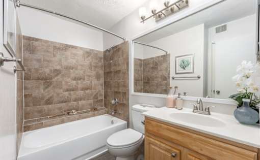 A bathroom with a white tub, sink, and toilet at Madison at Eden Brook, 21046