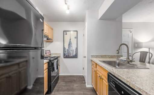 A kitchen with a black stove top oven and a black refrigerator at Madison at Eden Brook, 21046
