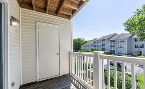 A white door is on a porch with a railing at Madison at Eden Brook, 21046