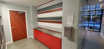 A hallway with a red door and a red and white striped wall.