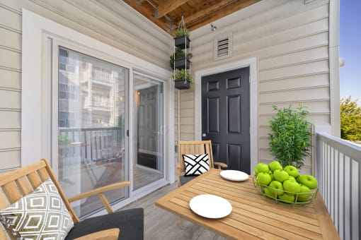 a patio with a wooden table and chairs and a black door at MetroPlace at Town Center, Camp Springs, 20746