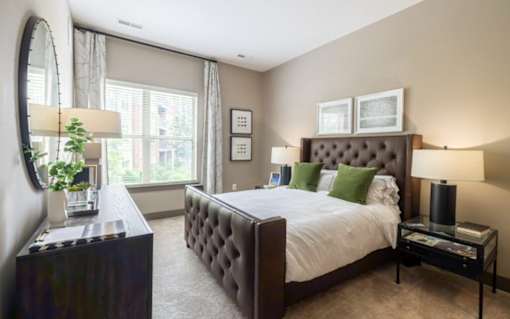 A bedroom with a large bed, a mirror, and a plant at Mira Upper Rock, Maryland, 20850