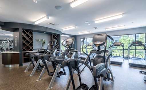 A gym with a row of treadmills and elliptical machines at Mira Upper Rock, Maryland, 20850