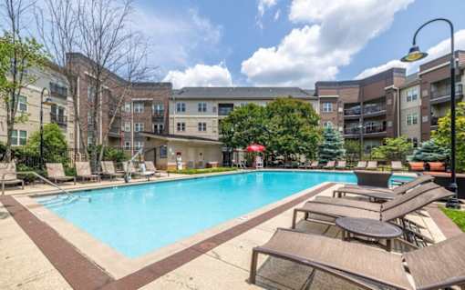 A large swimming pool surrounded by lounge chairs and umbrellas in a sunny day at Mira Upper Rock, Maryland, 20850