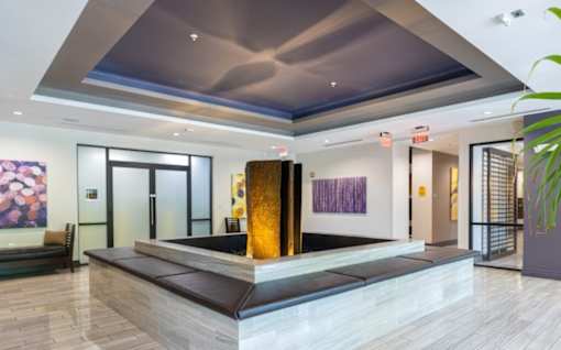 A modern lobby with a large artwork on the wall and a plant on the right at Mira Upper Rock, Maryland, 20850