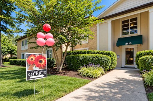 A sign for an office is in front of a building with a green awning.