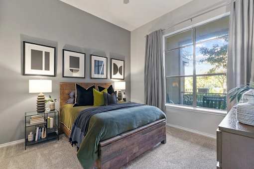 A bedroom with a bed, nightstand, and a window with curtains at Prairie Crossing, Texas