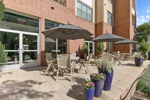A patio with chairs and umbrellas in front of a brick building at Prairie Crossing, Farmers Branch