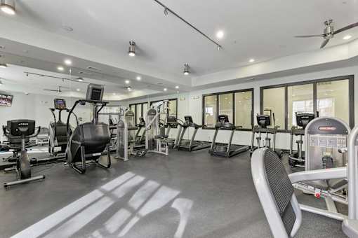A gym with a variety of equipment including treadmills, weights, and exercise machines at Prairie Crossing, Texas 75244