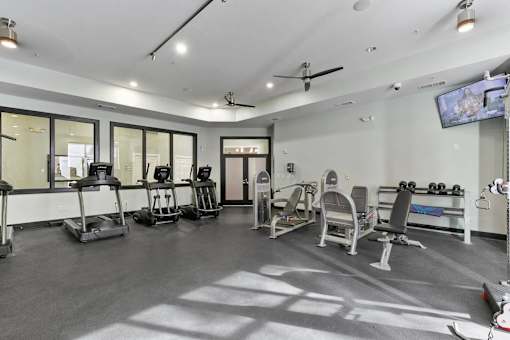 A spacious gym with a variety of equipment including treadmills, stationary bikes, and weight machines at Prairie Crossing, Farmers Branch, Texas