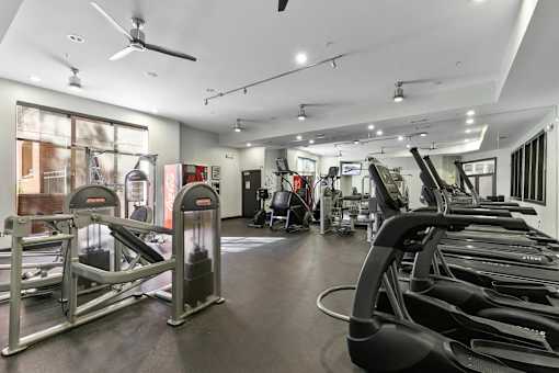 A gym with treadmills, elliptical machines, and a fan at Prairie Crossing, Farmers Branch, Texas