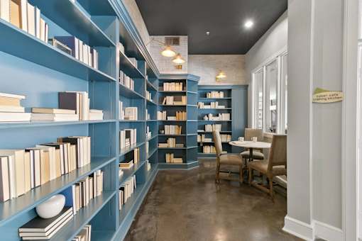 A room with blue bookshelves filled with books and a table with chairs at Prairie Crossing, Farmers Branch, TX