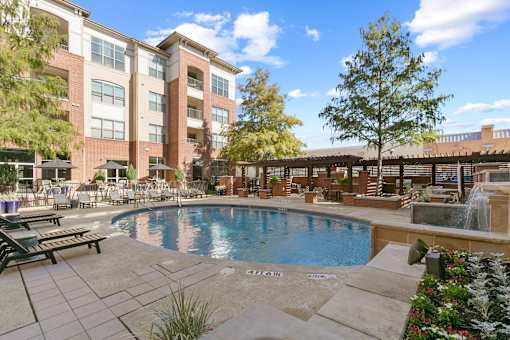 A large pool surrounded by a patio area with a building in the background at Prairie Crossing, Farmers Branch, Texas