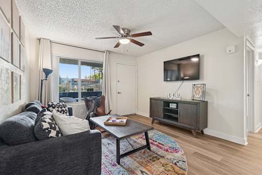 A living room with a grey couch, a coffee table, and a ceiling fan at Riviera Park, Chandler Arizona