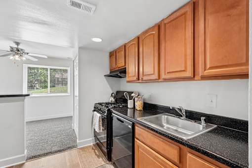 Kitchen with black appliances and wood cabinetry at The Brook At Columbia Apartments, Columbia, 21044