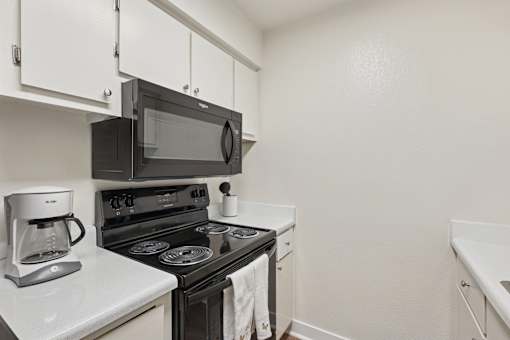 A black microwave oven is on the counter above a black stove at Riviera Park, Chandler Arizona