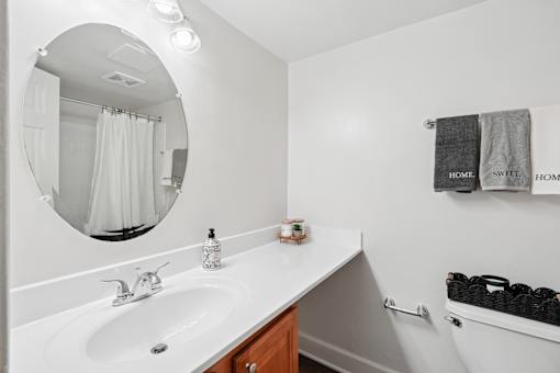 Modern bathroom with white countertop and oval mirror at The Brook At Columbia Apartments, Maryland