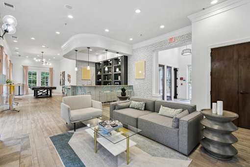 A modern living room with a grey sofa, a glass coffee table, and a wooden floor  at Poplar Glen Apartments, Columbia, MD, 21044.
