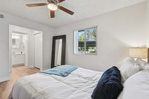 A bedroom with a bed, a ceiling fan, and a window with a view of trees at Riviera Park, Chandler Arizona
