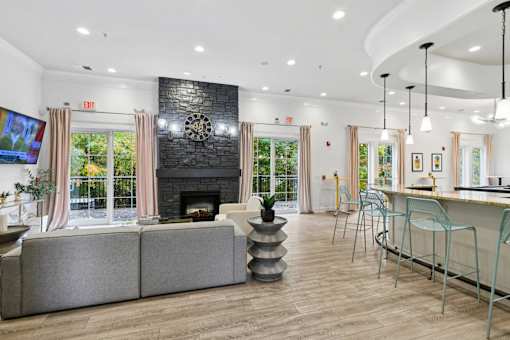 A living room with a grey couch, a fireplace, and a TV  at Poplar Glen Apartments, Columbia, MD, 21044.