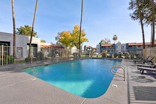 A large swimming pool surrounded by palm trees and benches at Riviera Park, Chandler Arizona