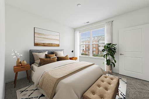 A bedroom with a large bed, a painting on the wall, and a window with a view of a building outside.