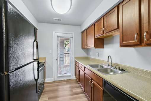 A kitchen with a black refrigerator and wooden cabinets  at Poplar Glen Apartments, Columbia, MD, 21044.