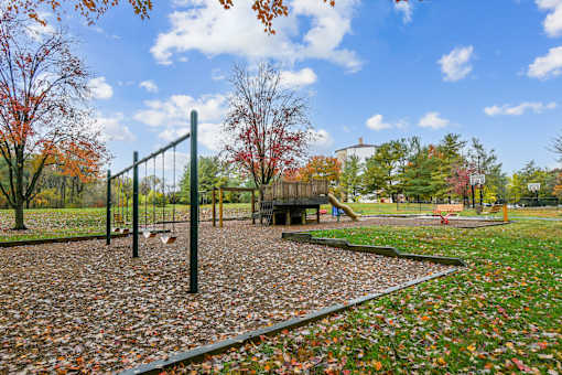 A playground with a swing set and a slide in the middle of a park  at Poplar Glen Apartments, Columbia, MD, 21044.