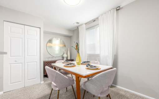 Dining room with round mirror and white table at The Brook At Columbia Apartments, Columbia