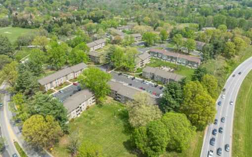 Aerial view of apartment community with parking and greenery at The Brook At Columbia Apartments, Maryland
