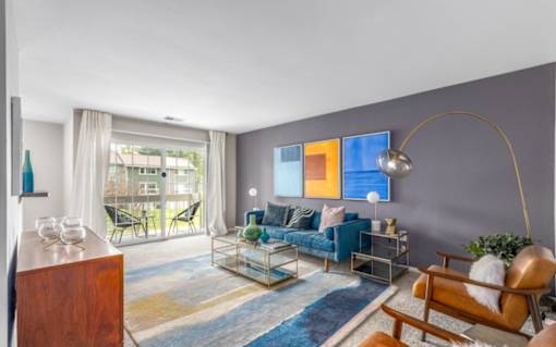 Living room with blue sofa and arched floor lamp at The Brook At Columbia Apartments, Maryland, 21044