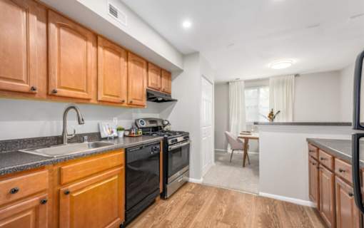 Galley kitchen with gas range and granite countertops at The Brook At Columbia Apartments, Columbia, MD