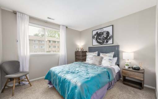 Bedroom with turquoise bedding and upholstered headboard at The Brook At Columbia Apartments, Columbia, 21044