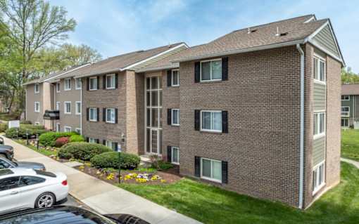 Three story brick apartment building with black shutters at The Brook At Columbia Apartments, Columbia, Maryland