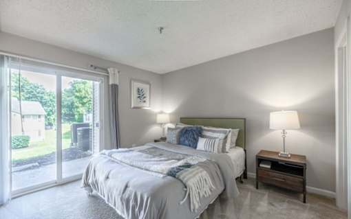 A bedroom with a large bed and a sliding glass door.