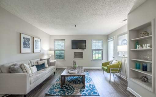 A living room with a couch, a chair, a coffee table, and a bookshelf.