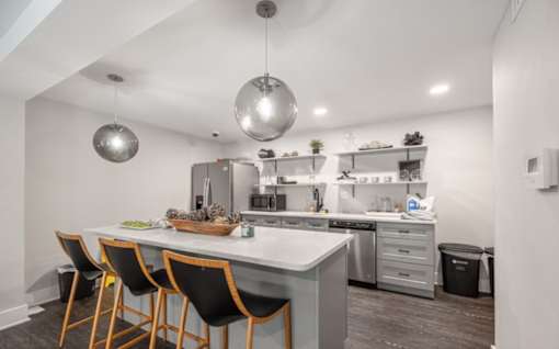 A modern kitchen with a white countertop and black chairs.