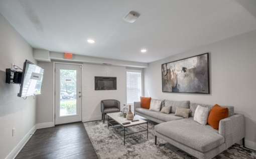 A living room with a grey couch, a coffee table, and a painting on the wall.