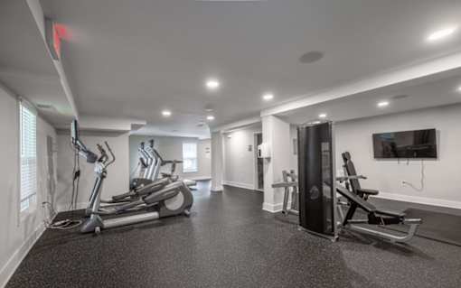 A spacious gym with treadmills, elliptical machines, and a television.