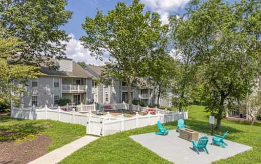 A white fence surrounds a green lawn with a white building in the background.