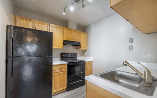 A kitchen with a black refrigerator, stove, and oven.