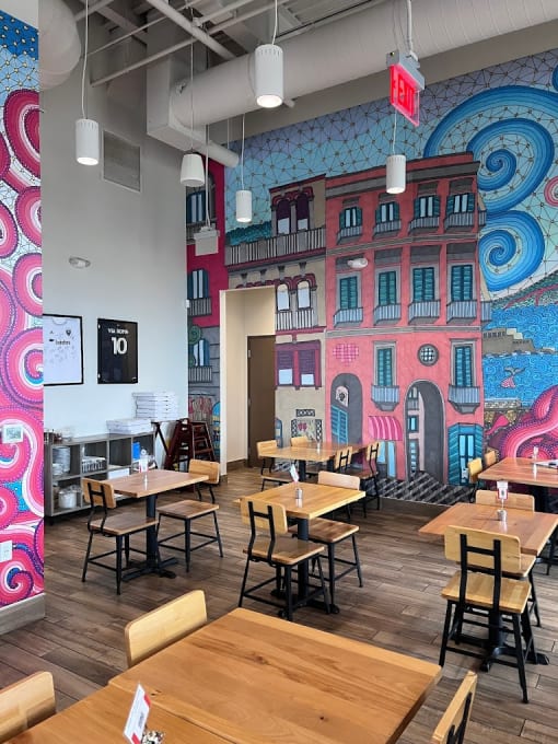 a mural in a restaurant with wooden tables and chairs