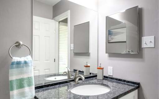A bathroom with a black granite countertop and a white sink.